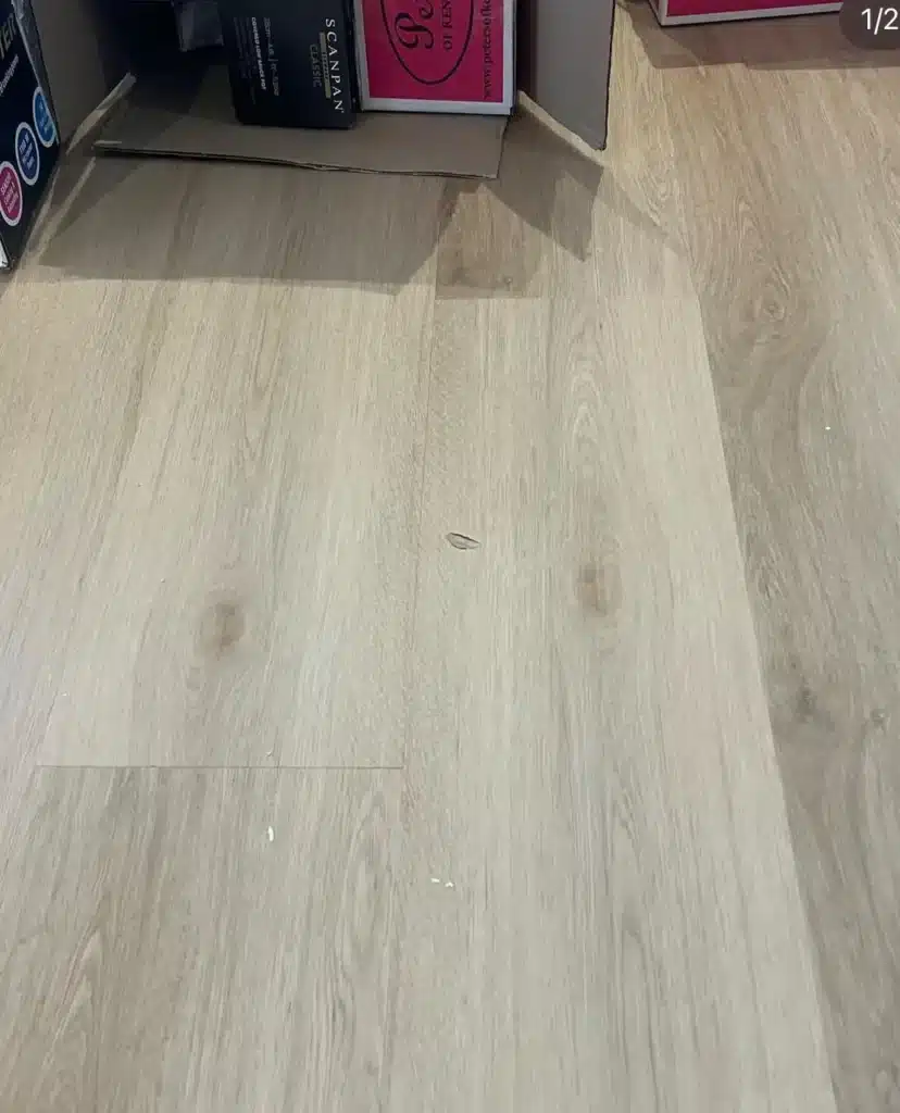 Chipped laminate floor with boxes in the background.