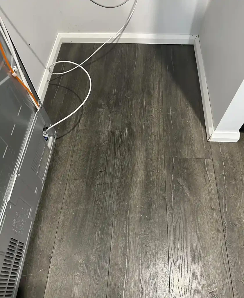 Scratched laminate floor after repair near kitchen fridge