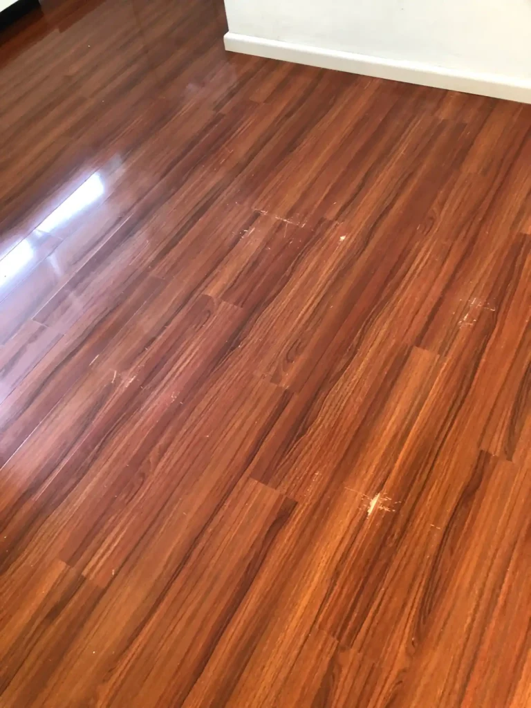 Laminate floor with visible scratches and damage before repair.