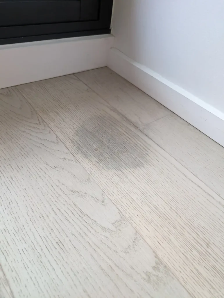 Water-damaged floor near skirting board before repair