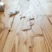 Wooden floorboards with creaks and repair tools nearby.