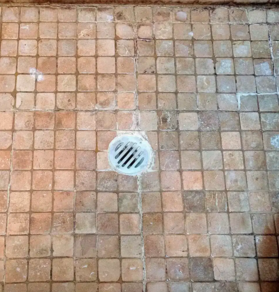 Bathroom shower floor with dirty, cracked grout before regrouting by Surface Care
