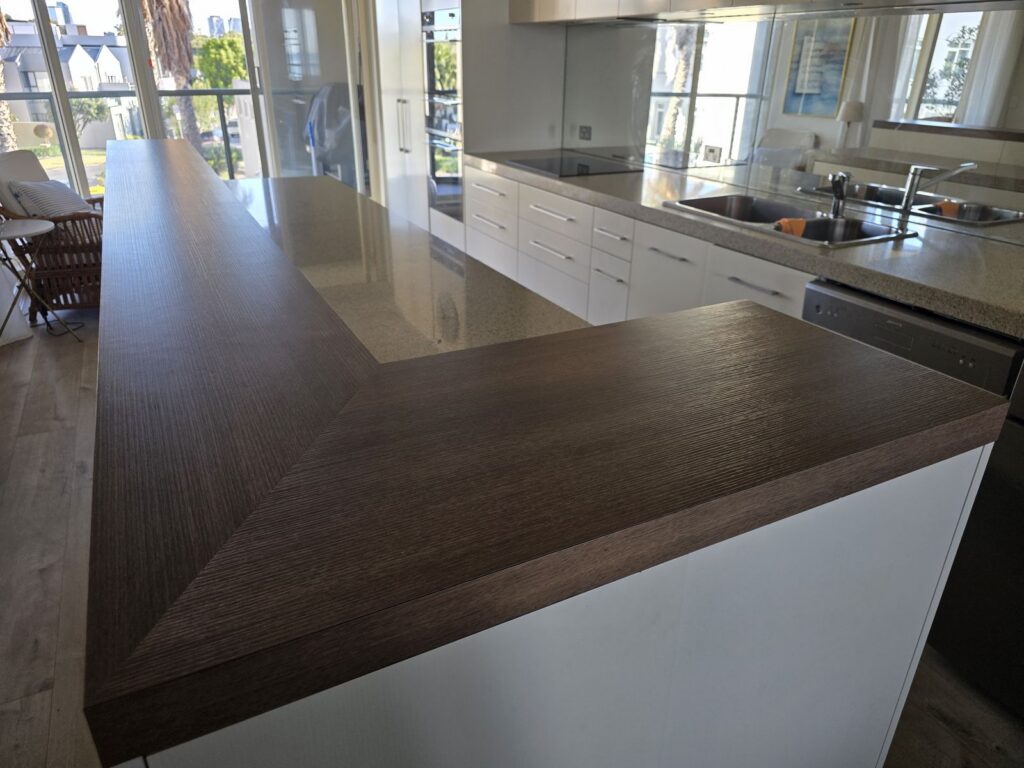 Dated dark wood-grain laminate benchtop before spray resurfacing, Port Melbourne kitchen