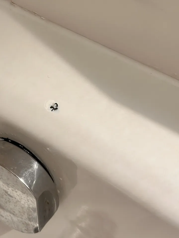 Enamelled steel bath with a small dark chip just above the overflow